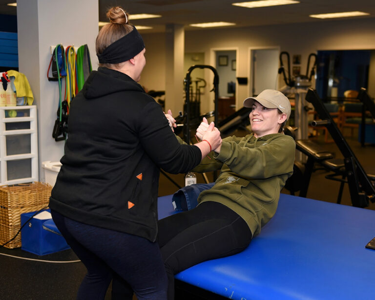 A trainer helps a woman to stand in the Push to Walk gym
